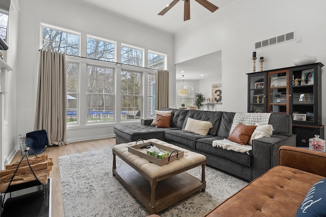 2693 Sanctuary Dr, Stevensville, MI 49127 - living room with a high ceiling, light wood finished floors, visible vents, crown molding, and ceiling fan