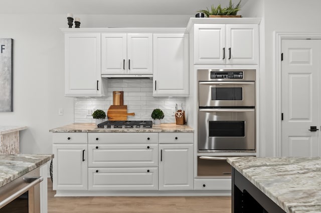 2693 Sanctuary Dr, Stevensville, MI 49127 - kitchen with light wood-style floors, a warming drawer, tasteful backsplash, appliances with stainless steel finishes, and white cabinetry