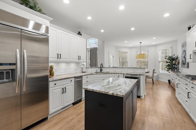 2693 Sanctuary Dr, Stevensville, MI 49127 - kitchen featuring tasteful backsplash, light wood-style floors, white cabinetry, a peninsula, and appliances with stainless steel finishes