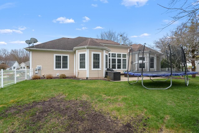 2693 Sanctuary Dr, Stevensville, MI 49127 - rear view of property featuring a lawn, fence, and a trampoline