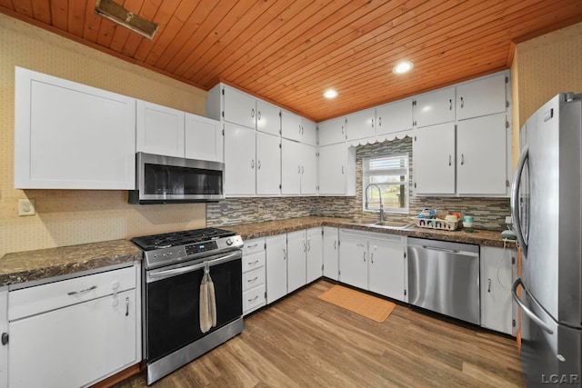 kitchen featuring stainless steel appliances, a sink, dark countertops, wood finished floors, and wood ceiling