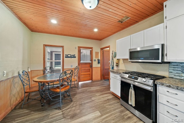kitchen featuring light wood-type flooring, wood ceiling, a wainscoted wall, stainless steel appliances, and white cabinets