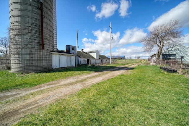 view of yard featuring fence and dirt driveway