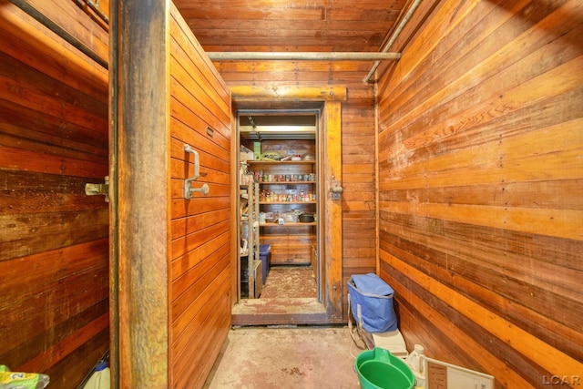 hallway featuring wood ceiling, wooden walls, and concrete floors