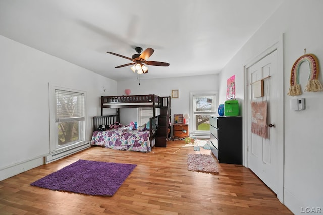 bedroom featuring wood finished floors, baseboard heating, and ceiling fan