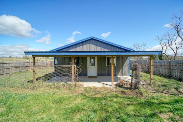 rear view of property featuring board and batten siding, a lawn, a fenced backyard, and a patio