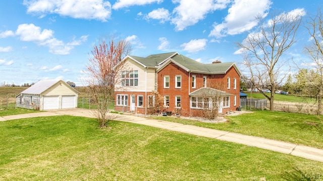 traditional-style home with concrete driveway, fence, an outbuilding, a front yard, and brick siding