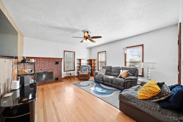 living area featuring a fireplace, hardwood / wood-style floors, a textured ceiling, and a ceiling fan