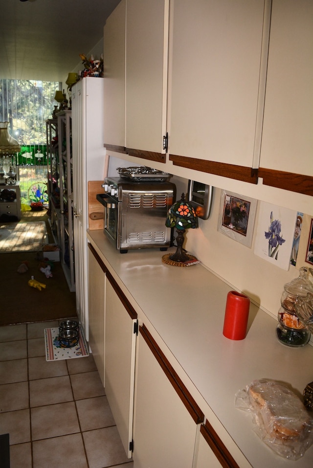 kitchen featuring tile patterned floors, light countertops, white cabinets, and a toaster