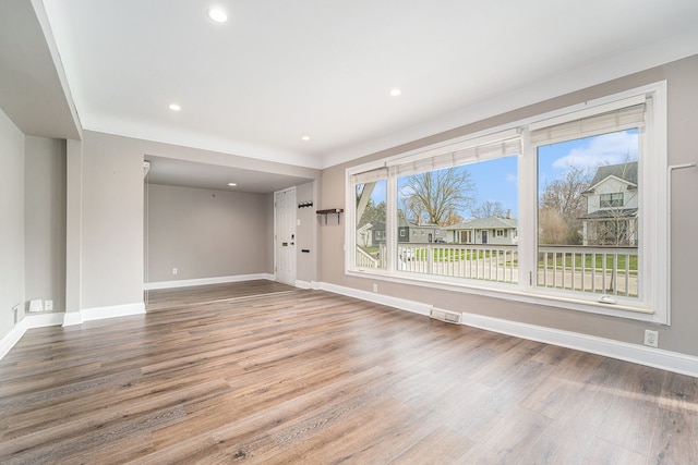 unfurnished living room with wood finished floors, baseboards, and recessed lighting