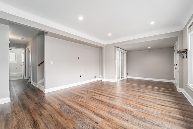 unfurnished living room with baseboards, stairs, wood finished floors, and recessed lighting