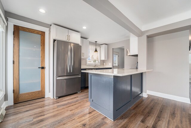 kitchen with freestanding refrigerator, white cabinets, wood finished floors, a peninsula, and baseboards