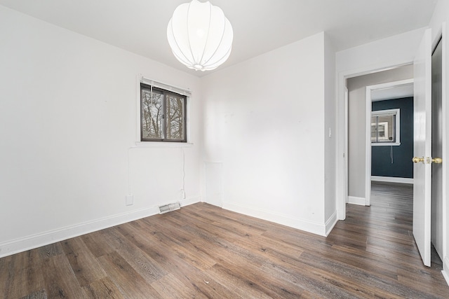 spare room featuring baseboards and wood finished floors