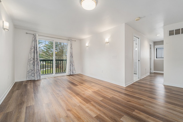 empty room featuring wood finished floors, baseboards, and a smoke detector
