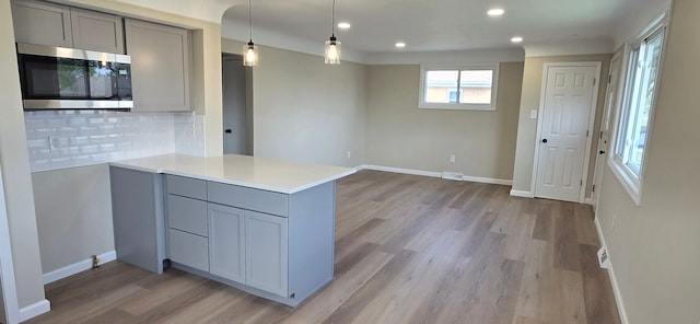 kitchen with light wood-style floors, recessed lighting, stainless steel microwave, and gray cabinets