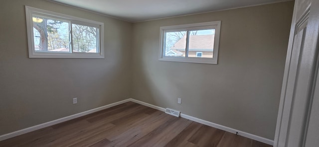 spare room featuring baseboards, visible vents, crown molding, and dark wood-style floors
