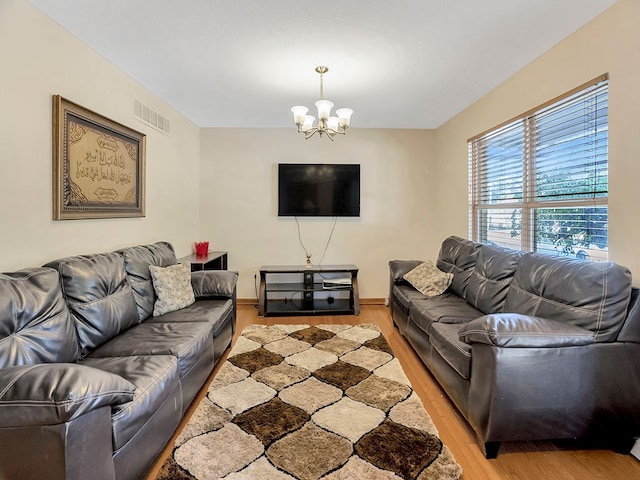 living area featuring wood finished floors, visible vents, and an inviting chandelier