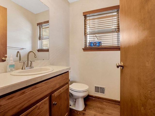 bathroom with wood finished floors, visible vents, toilet, vanity, and baseboards