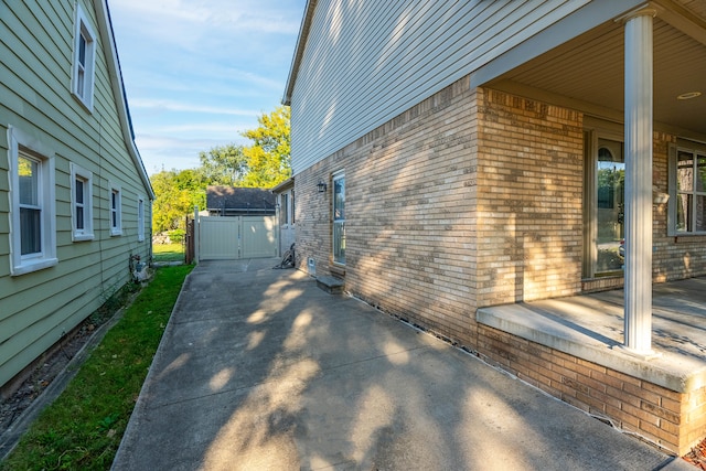 view of side of home featuring brick siding and a gate