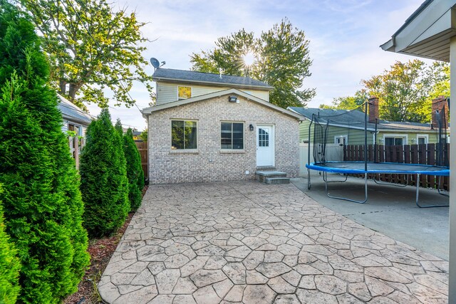 rear view of property with fence, a patio area, entry steps, and a trampoline