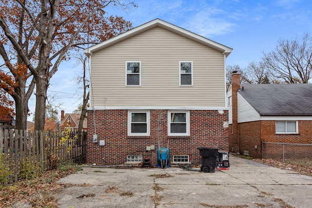 rear view of house with brick siding and fence