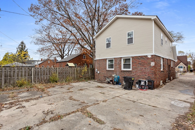 rear view of property featuring fence and brick siding
