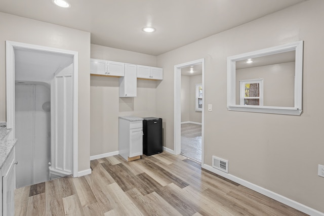 kitchen featuring baseboards, white cabinetry, visible vents, and light wood-type flooring
