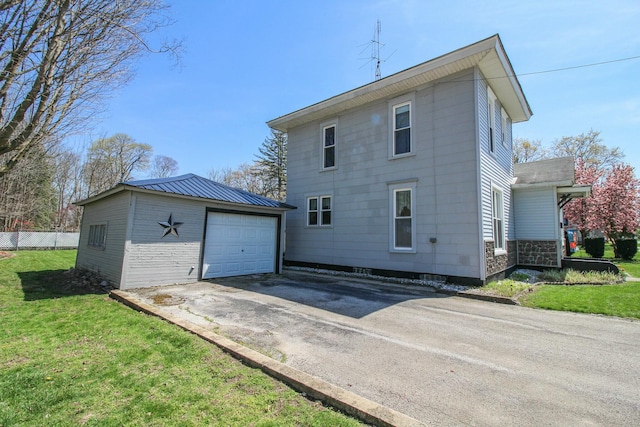 exterior space featuring a lawn, an outdoor structure, aphalt driveway, and a detached garage