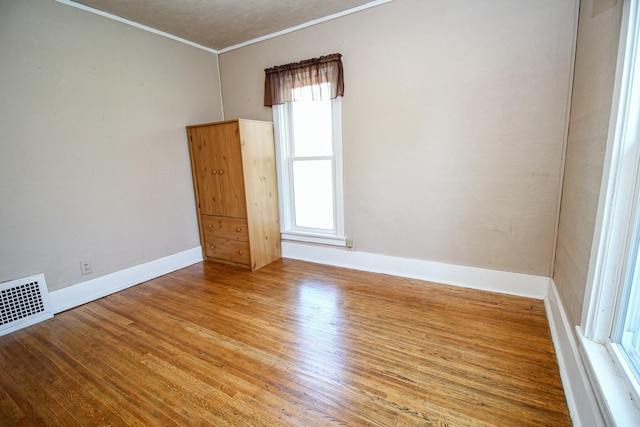 empty room with visible vents, a healthy amount of sunlight, and crown molding