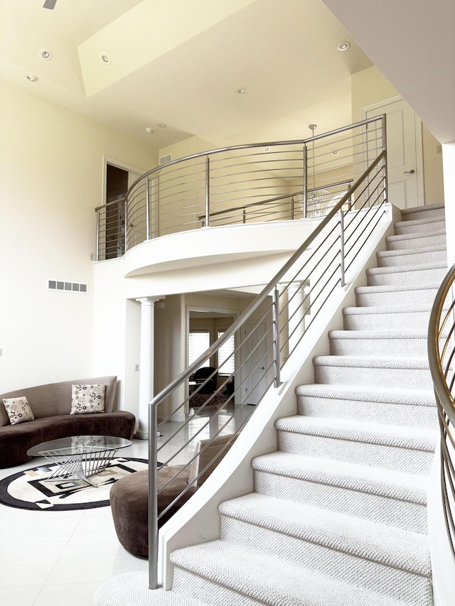 staircase with recessed lighting, visible vents, and a towering ceiling