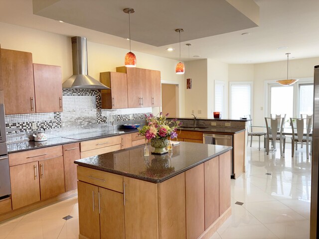 kitchen with a sink, wall chimney exhaust hood, black electric stovetop, a peninsula, and tasteful backsplash