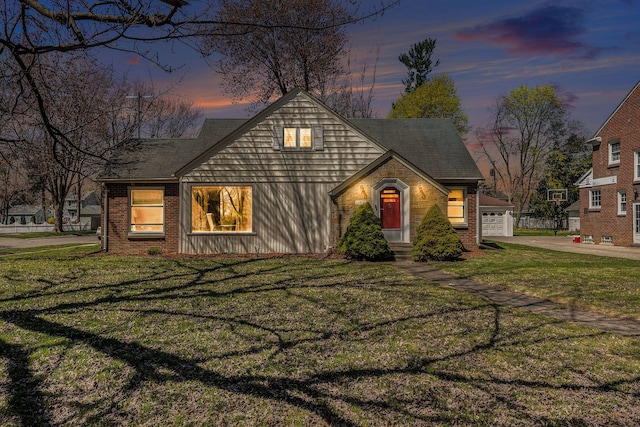 view of front of property featuring brick siding, driveway, a front lawn, and a garage
