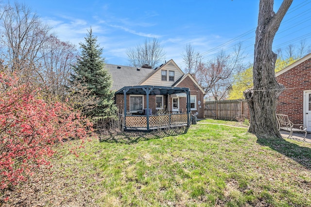 back of house featuring a lawn, brick siding, fence, and a pergola