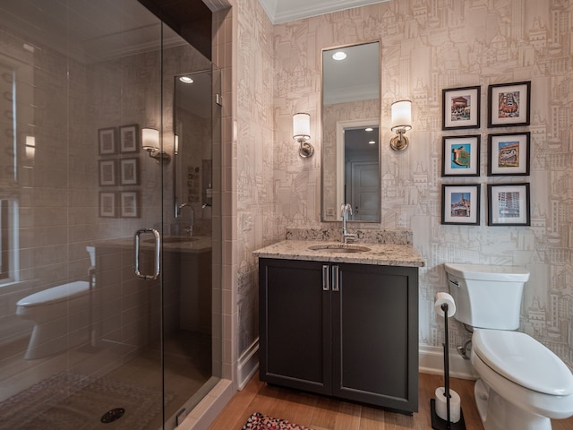 bathroom featuring wood finished floors, a stall shower, vanity, toilet, and ornamental molding