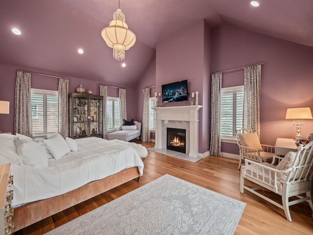 bedroom featuring recessed lighting, a high end fireplace, wood finished floors, baseboards, and high vaulted ceiling