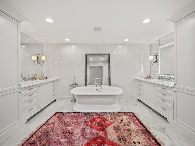 bathroom featuring marble finish floor, a freestanding bath, two vanities, visible vents, and recessed lighting