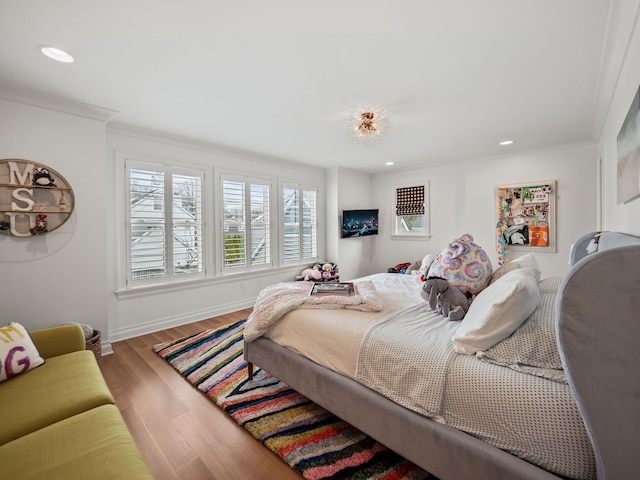 bedroom featuring baseboards, wood finished floors, recessed lighting, and crown molding