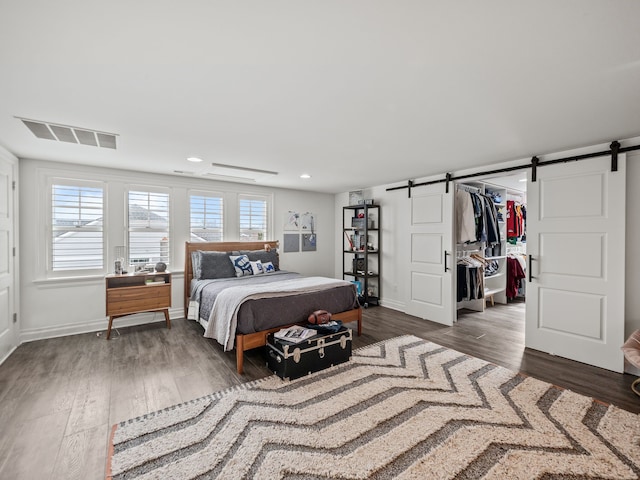 bedroom with a barn door, visible vents, a walk in closet, and recessed lighting
