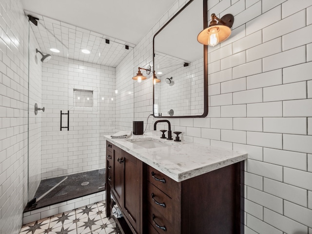 full bath with a shower stall, vanity, and tile walls