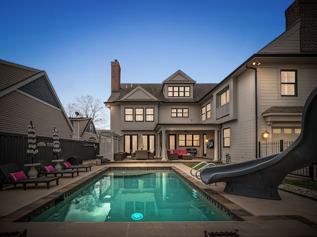 back of property with an outdoor living space, a chimney, fence, a patio, and a fenced in pool