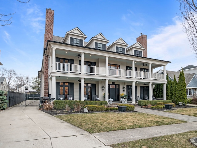 view of front of property with a front lawn, a ceiling fan, a gate, and a balcony