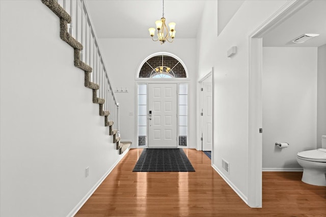 entrance foyer featuring visible vents, stairs, wood finished floors, and a chandelier