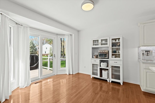 interior space with visible vents, light wood finished floors, and baseboards