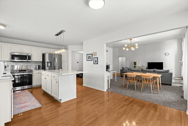 kitchen with an inviting chandelier, light countertops, white cabinets, and stainless steel appliances