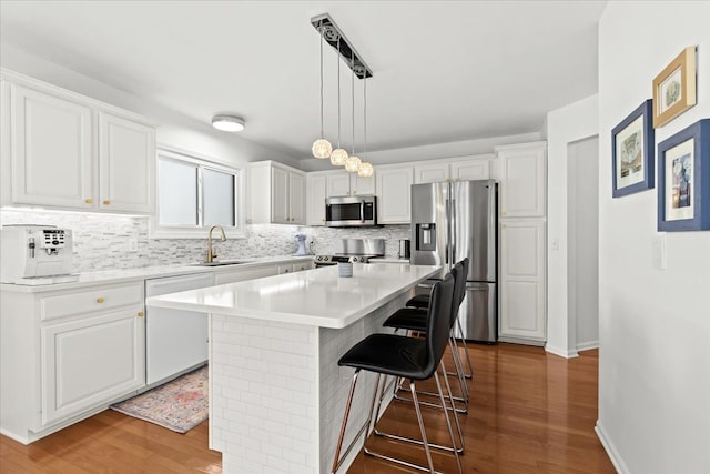kitchen with backsplash, stainless steel appliances, a sink, and wood finished floors