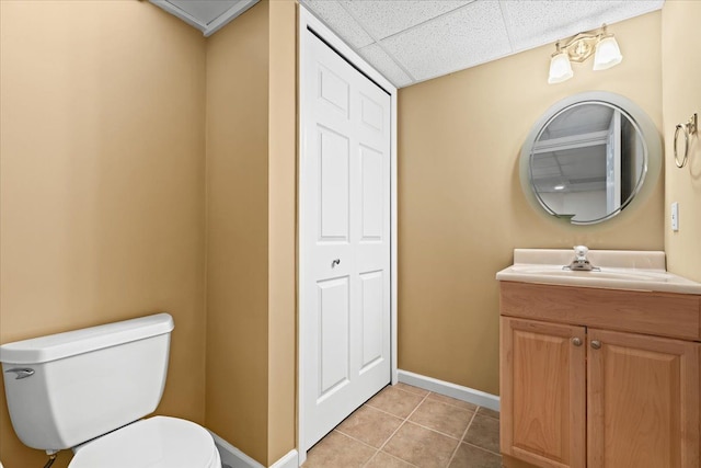bathroom with a paneled ceiling, baseboards, tile patterned floors, vanity, and toilet