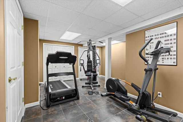 exercise area featuring baseboards and a paneled ceiling