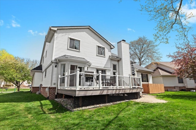back of house featuring a lawn, a deck, and a chimney