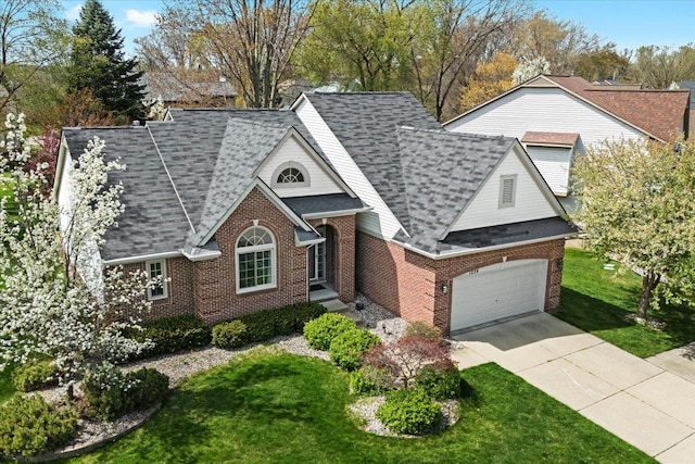 traditional-style house featuring an attached garage, a shingled roof, brick siding, a front yard, and concrete driveway