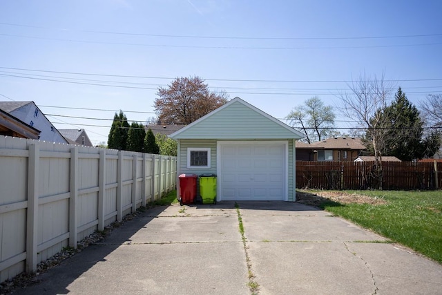 detached garage featuring fence and concrete driveway